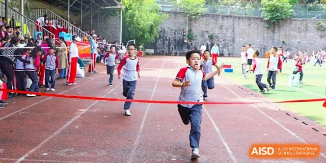 A CHONGQING WEIMING SCHOOL student winning a foot race, crossing the finish line tape with determination.