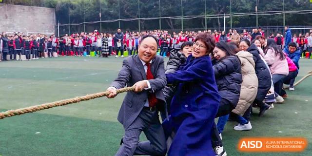 CHONGQING WEIMING SCHOOL faculty members or teachers engaging in a friendly game of tug-of-war during a school event.