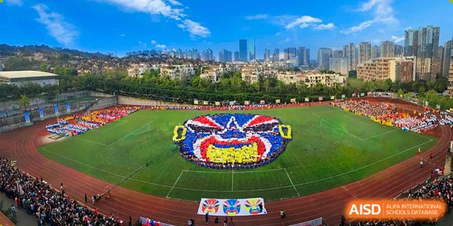 CHONGQING WEIMING SCHOOL students forming a large, colorful pattern on the sports field during an assembly or event, viewed from above.