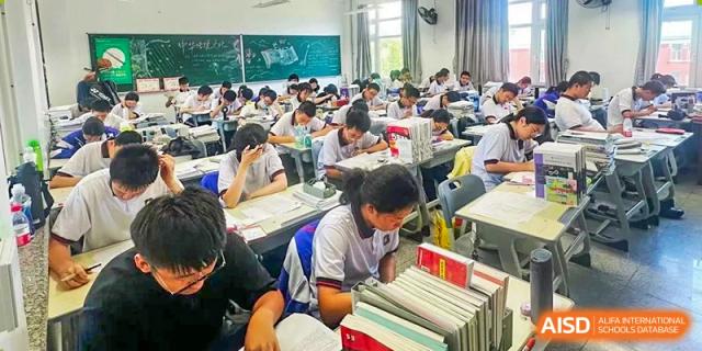 A view of a busy classroom at Dalian No.24 High School Cambridge International A-Level Centre with many students seated at their desks, engaged in a lesson or work.