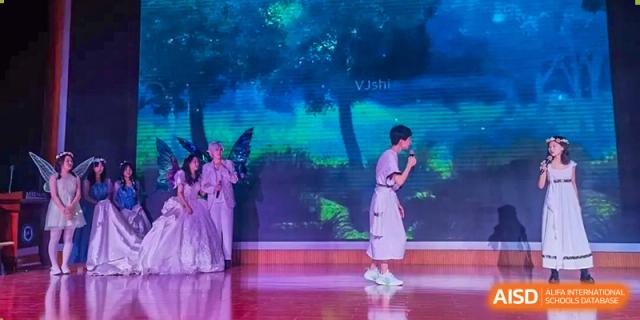 A student from Dalian No.24 High School Cambridge International A-Level Centre bows on a stage during a performance with a dark, artistic blue and green light backdrop.