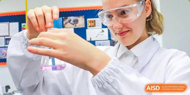 A student from Dulwich College Shanghai Puxi wearing a lab coat and safety glasses in a science lab.