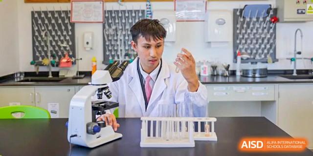 A student from Dulwich College Shanghai Puxi wearing a lab coat and safety glasses in a science lab.