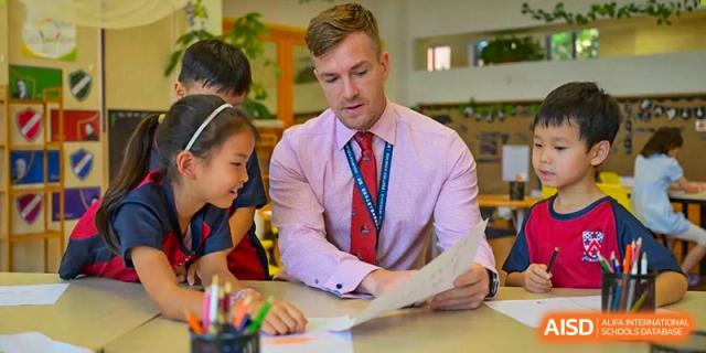 A teacher at Dulwich College Shanghai Puxi helping students in a classroom.