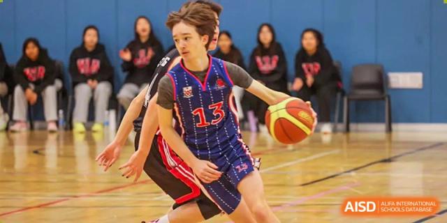 A student from Dulwich College Shanghai Puxi with jersey number 13 playing basketball.