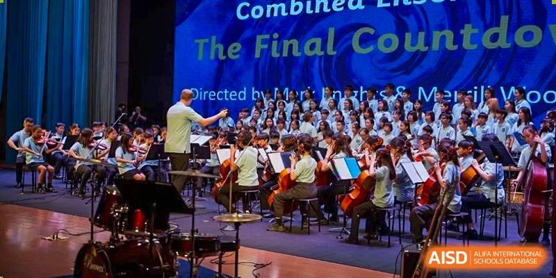An orchestra and choir from Dulwich College Shanghai Puxi performing on stage.