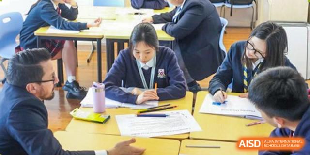 A female student at Dulwich College Suzhou is sitting at her desk, concentrating on her work. Her hands are on her desk, and there are a couple of pencils in front of her.