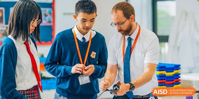 A male student at Dulwich College Suzhou and a male teacher with glasses are looking down and collaborating on a project or an assignment.