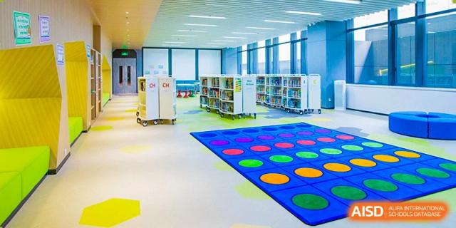 A modern children's library at Dulwich College Suzhou with white bookshelves and a large, colorful polka-dot mat on the floor.