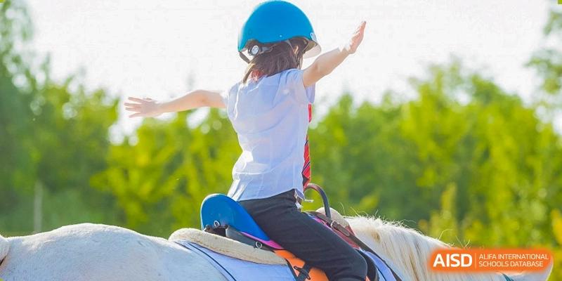 A student from Dulwich College Suzhou is riding a horse while wearing a helmet.