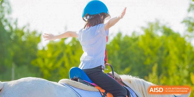 A student from Dulwich College Suzhou is riding a horse while wearing a helmet.