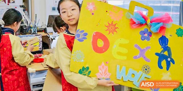 A young student from Dulwich College Suzhou holds up a bright yellow sign.