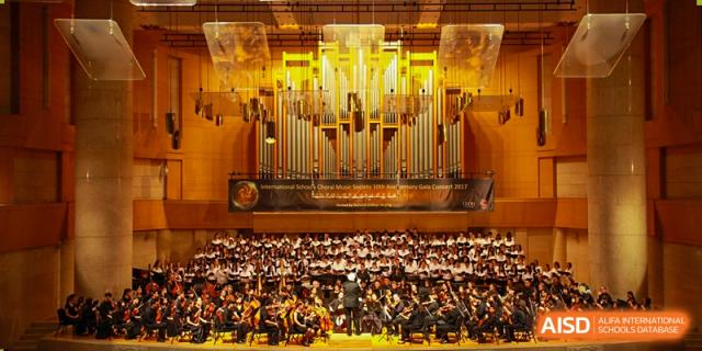 A large orchestra and choir from Dulwich College Suzhou perform in a concert hall.