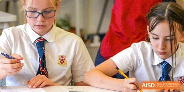 Two students from Dulwich College Suzhou are sitting at a desk and writing.
