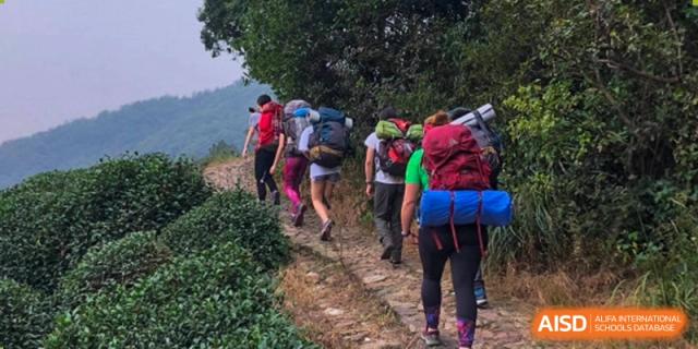 A group of students and teachers from Dulwich College Suzhou hike up a path on a beautiful day.