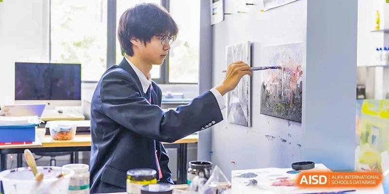 A male student from Dulwich International Suzhou High School Programme working on a painting in an art class.