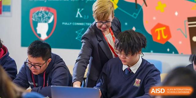 A teacher from Dulwich International Suzhou High School Programme assisting a student with a project on a laptop.
