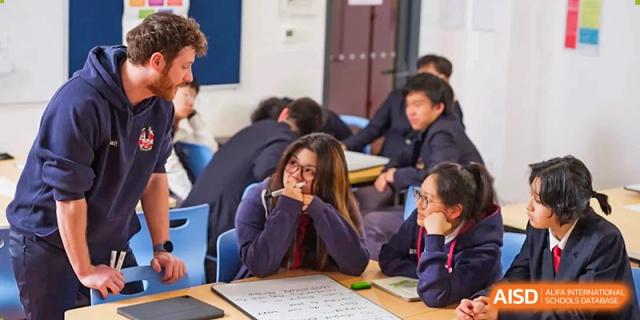 A group of students from Dulwich International Suzhou High School Programme in a classroom, with one student looking engaged in a discussion.