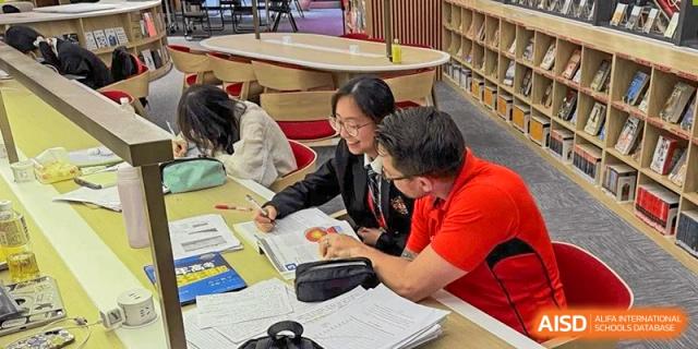 Students from Dulwich International Suzhou High School Programme working together on a project at a table.