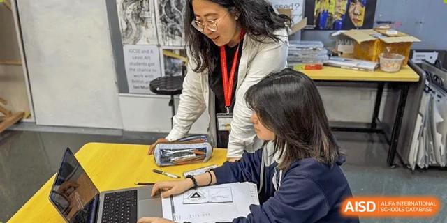 A teacher from Dulwich International Suzhou High School Programme helping a student with their work in a classroom.