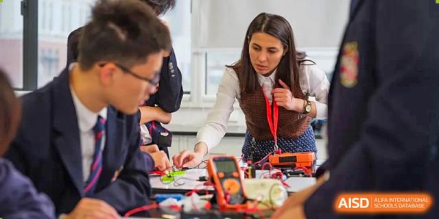 A female teacher from Dulwich International Suzhou High School Programme helping students with a hands-on science project.