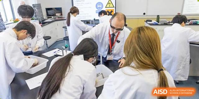 A teacher and students from Dulwich International Suzhou High School Programme collaborating on a science experiment in a lab.