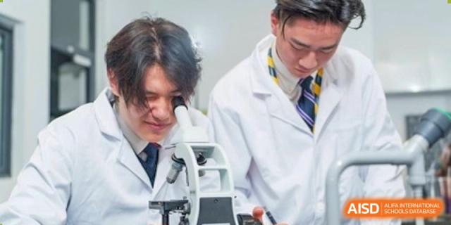 A male student from Dulwich International Suzhou High School Programme looking through a microscope in a science lab.
