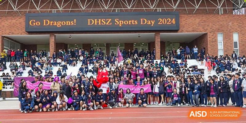 Students from Dulwich International Suzhou High School Programme gathered at a sports day event, with a sign that reads "DHSZ Sports Day 2023."