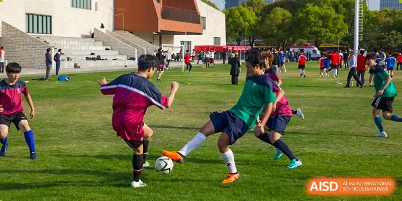 Two students from Dulwich International Suzhou High School Programme playing soccer on a grassy field.