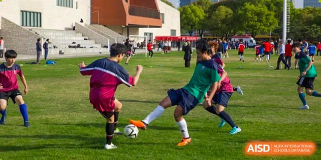 Two students from Dulwich International Suzhou High School Programme playing soccer on a grassy field.