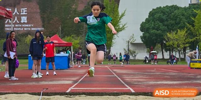 A student from Dulwich International Suzhou High School Programme performing a long jump at a track and field event.
