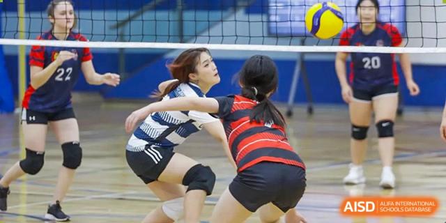 Two female students from Dulwich International Suzhou High School Programme playing volleyball.