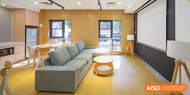 A living room area in a student dormitory at Dulwich International Suzhou High School Programme, with a large gray couch and coffee table.