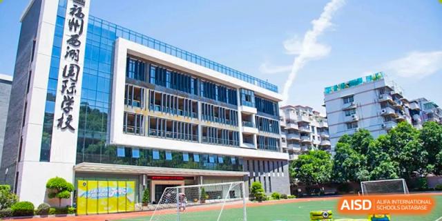 The modern school building with a sports field and a soccer goal at Fuzhou Lakeside International School.