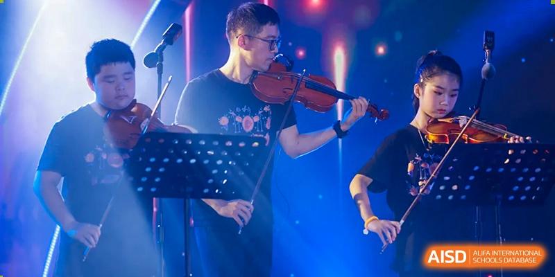 A musician playing a violin on stage at a Fuzhou Lakeside International School event.