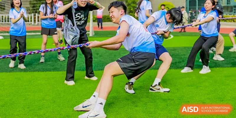 A student participating in a tug-of-war competition on a field at Fuzhou Lakeside International School.
