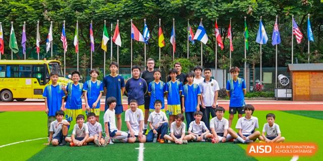 A sports team group photo with a teacher and international flags in the background at Fuzhou Lakeside International School.