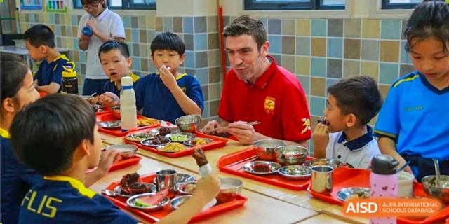 A student and a teacher or staff member eating a meal together in the cafeteria at Fuzhou Lakeside International School.