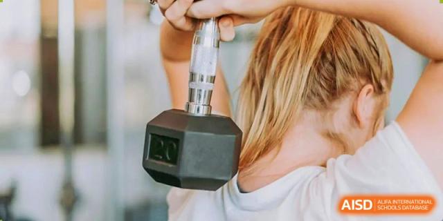 A close-up of a student or teacher holding a dumbbell in the school gym at Fuzhou Lakeside International School.