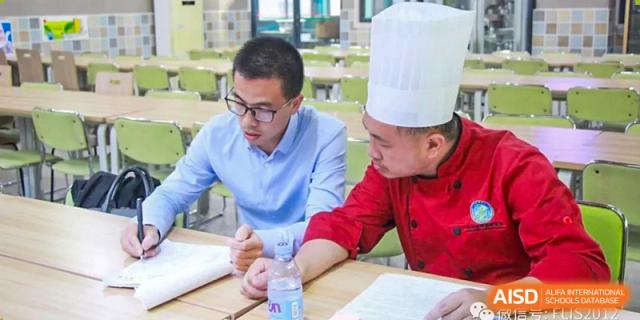 An instructor talking to a student wearing a chef's hat during a cooking class at Fuzhou Lakeside International School.
