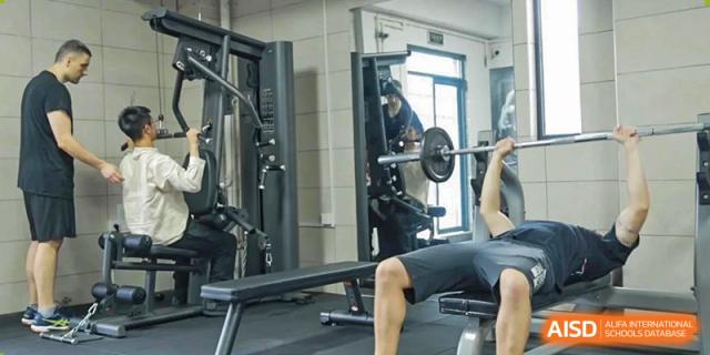 A student using a weight machine in the school's fitness center at Fuzhou Lakeside International School.
