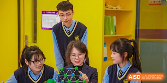Grand International School students in uniform collaborating on a hands-on model or project at a table.