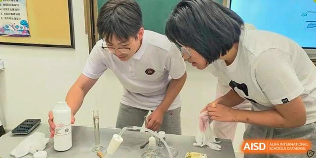Two Grand International School students in white shirts working together on a science experiment at a lab bench.