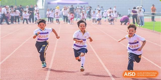 A young Grand International School student running in a race on an outdoor track during a sports day event.