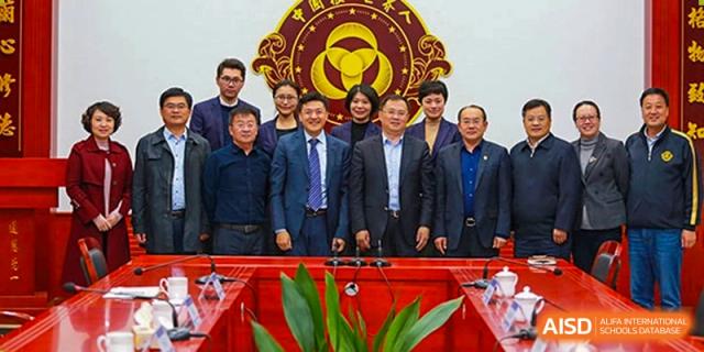 A group of Grand International School administrators and guests posing for a formal photo in front of a school emblem during an event.