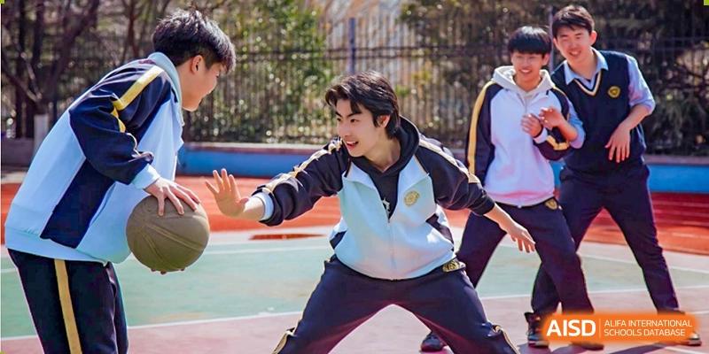 A Grand International School student dribbling a basketball and playing outdoors with classmates.