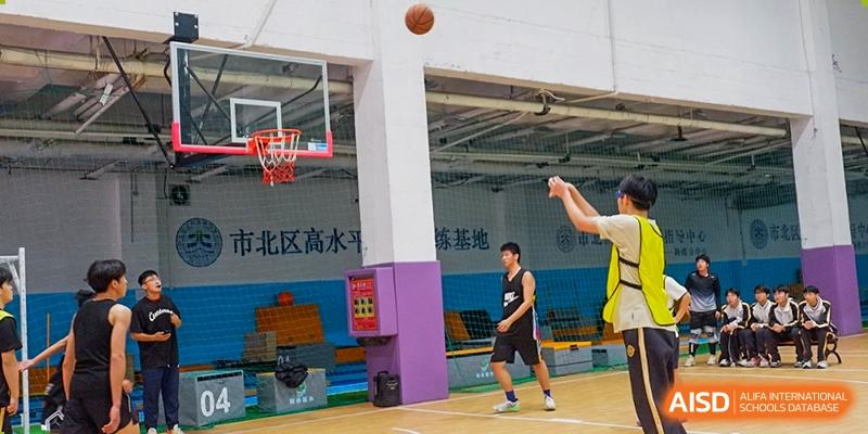 Grand International School students practicing or playing basketball on an outdoor court near a wall with a mural.