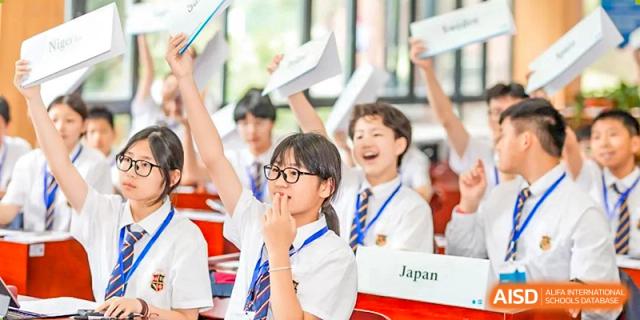 A group of students at HAILIANG FOREIGN LANGUAGE SCHOOL happily raises their hands in a classroom.
