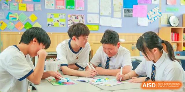 Two students at HAILIANG FOREIGN LANGUAGE SCHOOL work on a drawing together at a table.