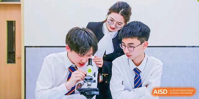 A teacher at HAILIANG FOREIGN LANGUAGE SCHOOL helps two students with a microscope during a science class.